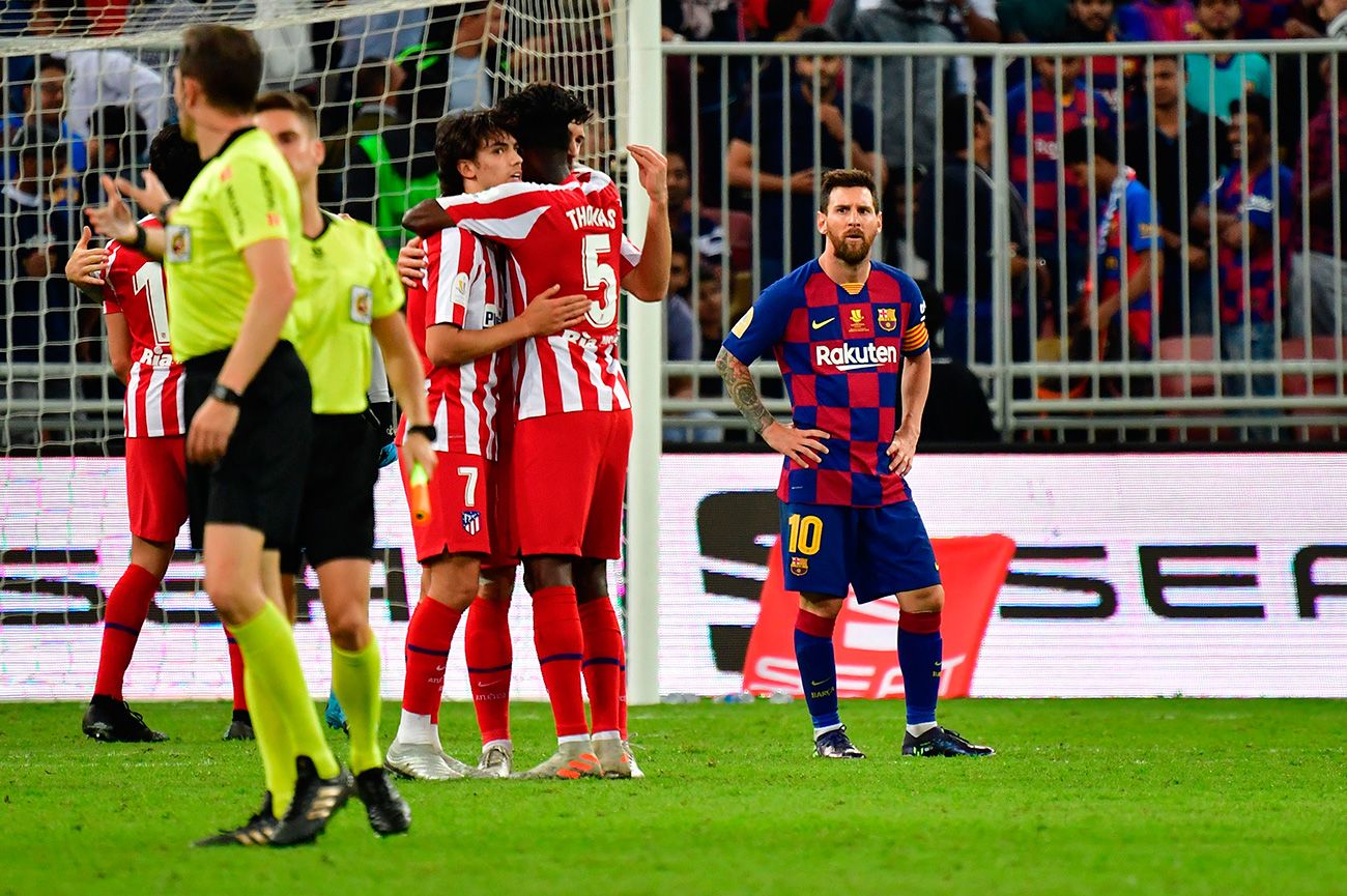 Leo Messi looks askance to the players of the Athletic celebrate a goal