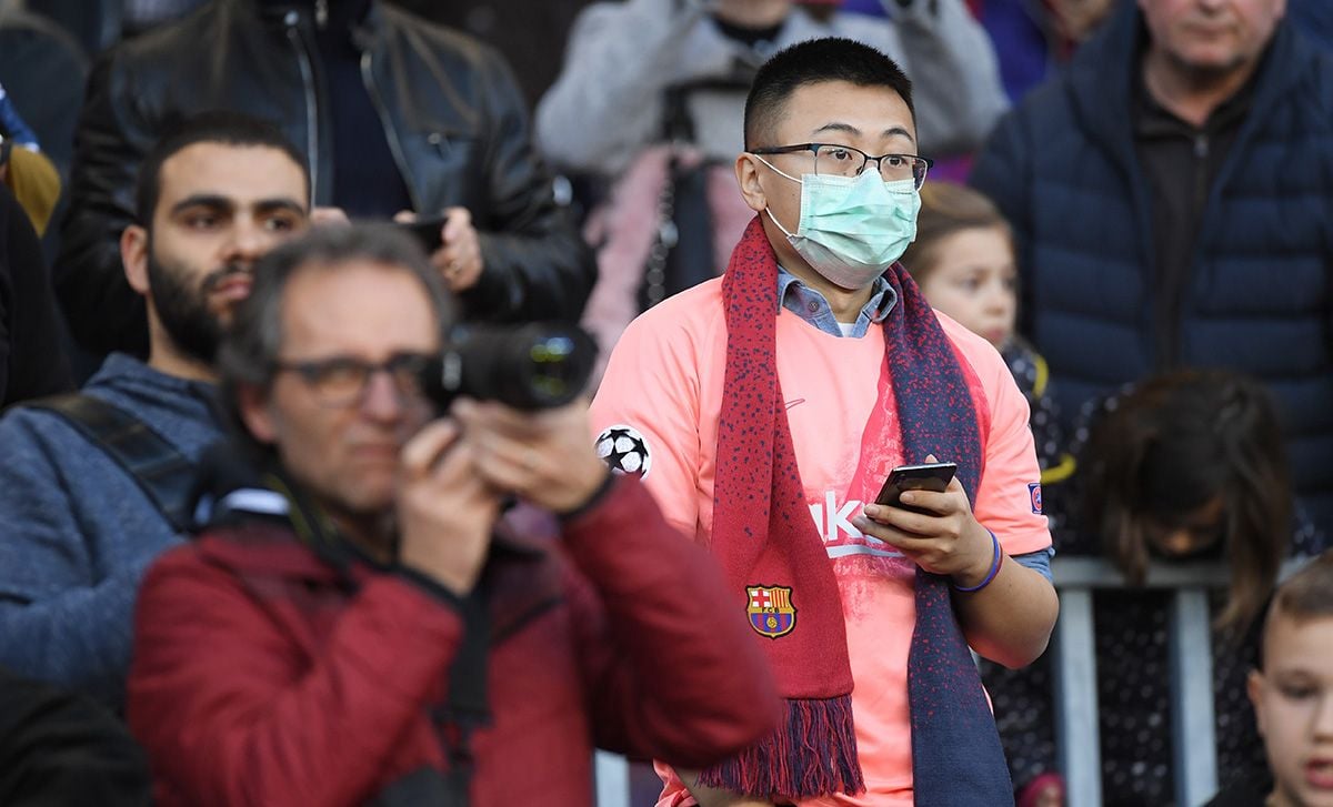 Un aficionado chino, con el móvil y mascarilla en el Camp Nou