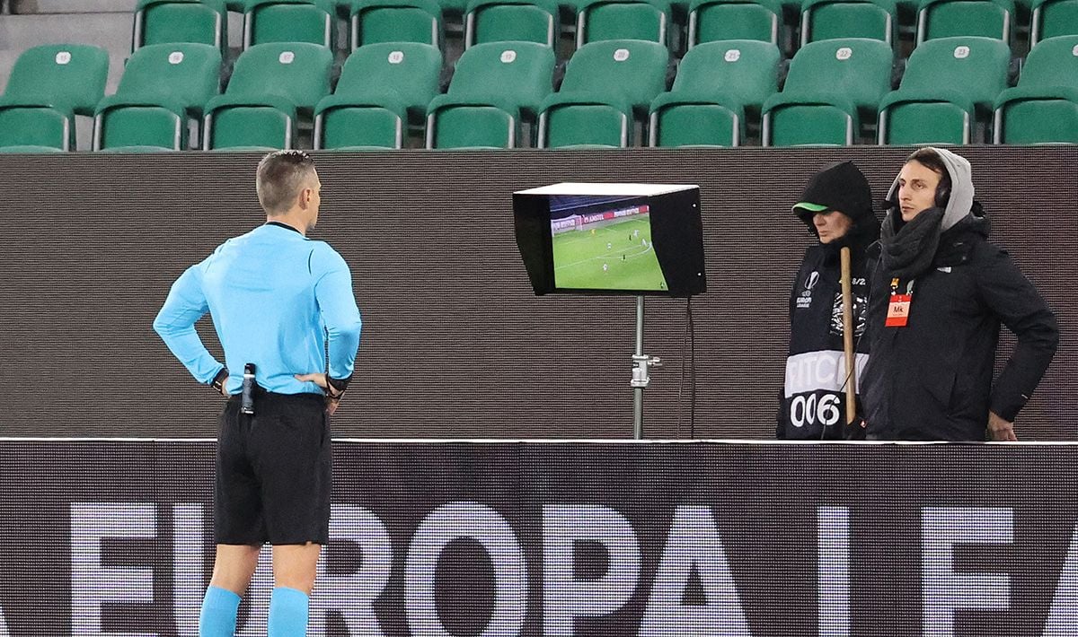 El árbitro, revisando un posible penalti en un partido de UEFA Europa League