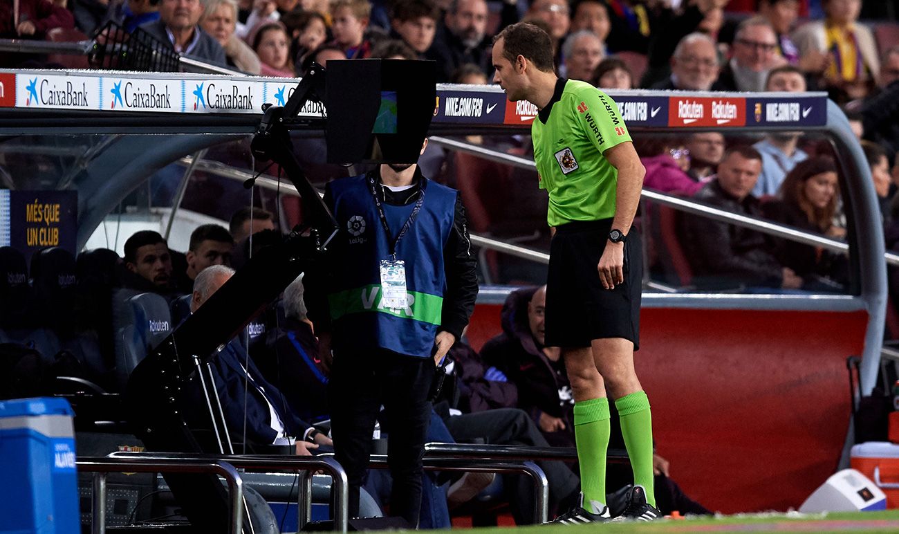 A referee reviews a played in the VAR in the Camp Nou