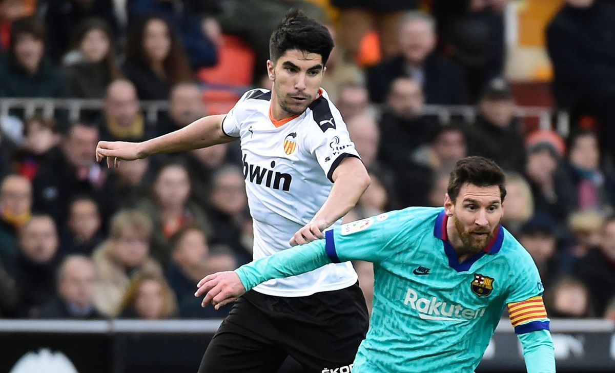 Carlos Soler en un duelo con Leo Messi