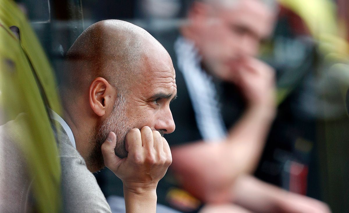 Pep Guardiola, seated in the bench during a match