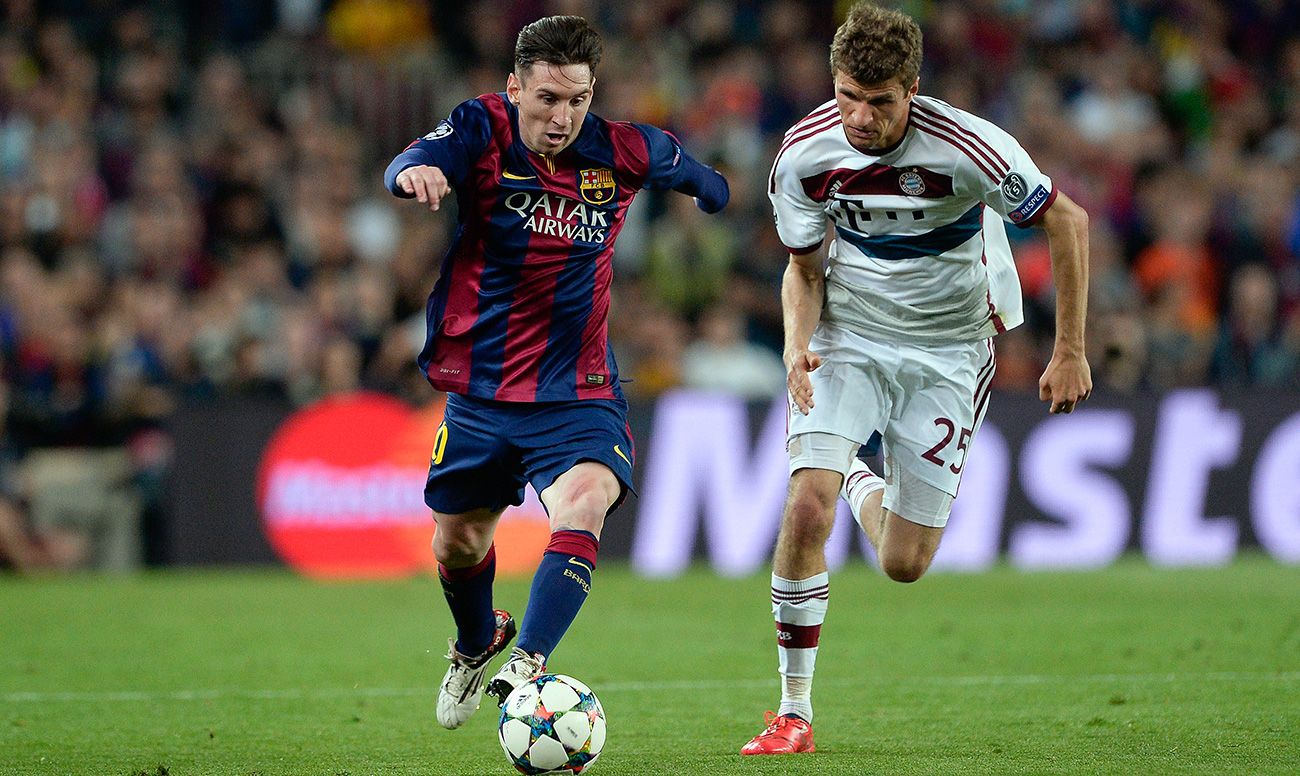 Leo Messi drives in front of the look of Thomas Muller