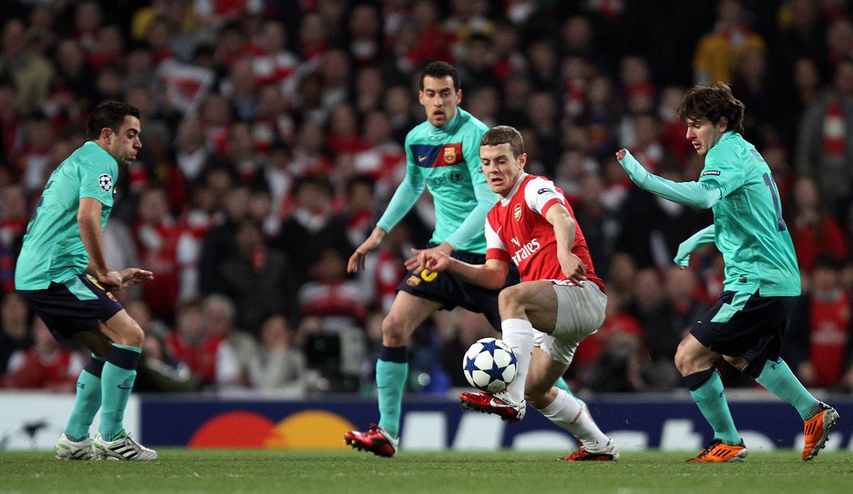 Wilshere, defended by Xavi, Busquets and Messi