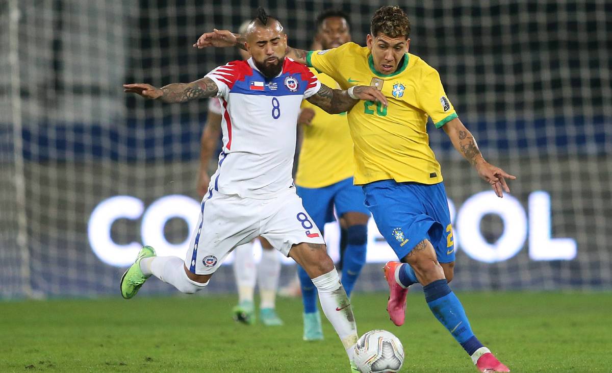 Arturo Vidal y Roberto Firmino disputan el balón en el Brasil-Chile