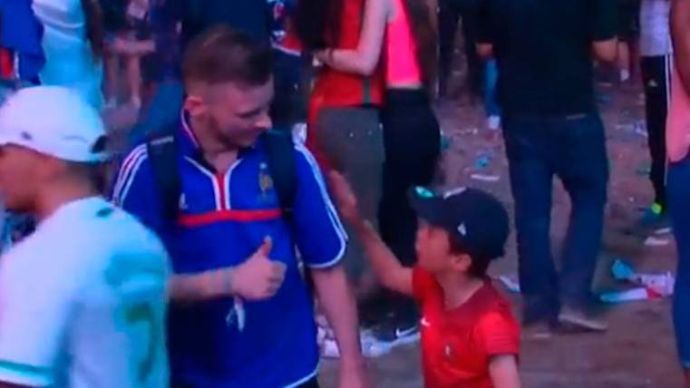 A Portuguese boy treats to comfort to a fan of France after the final of the Eurocopa