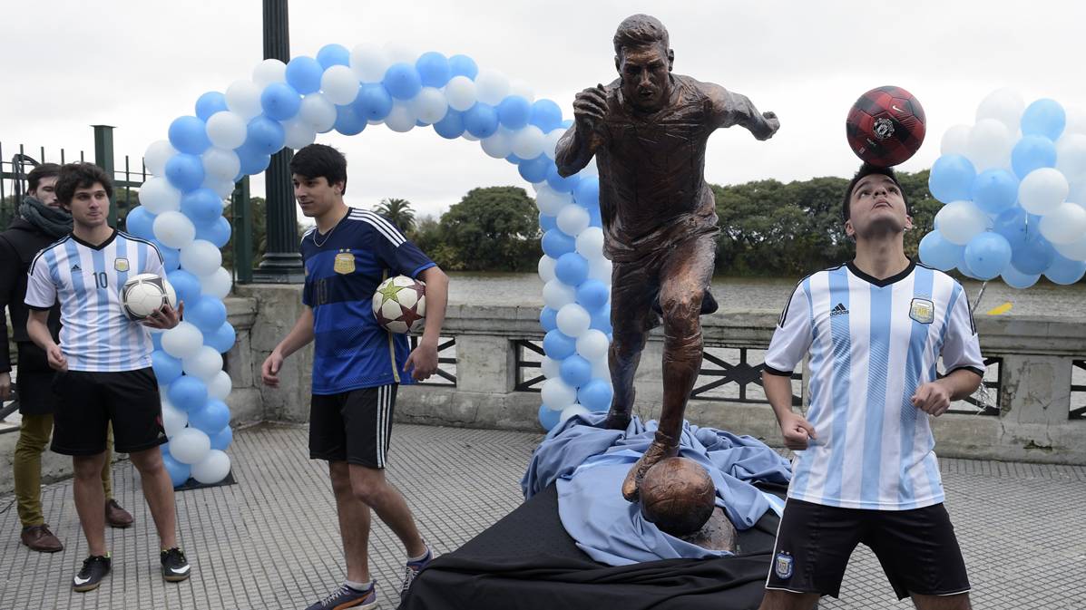 Argentinian fans, beside a sculpture of Leo Messi