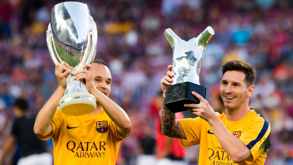 Andrés Iniesta and Leo Messi, raising two trophies in an image of archive
