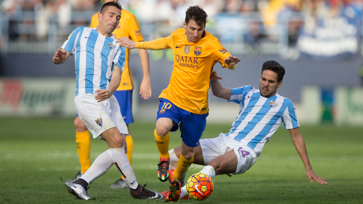 Leo Messi, soportando la entrada de dos jugadores del Málaga