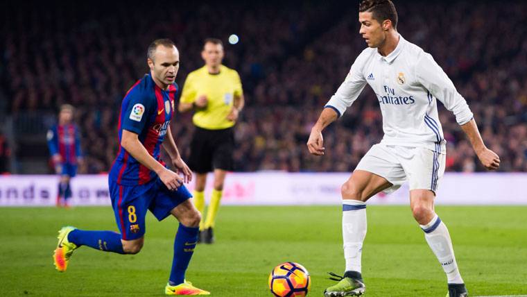 Andrés Iniesta, pugnando por un balón con Cristiano Ronaldo