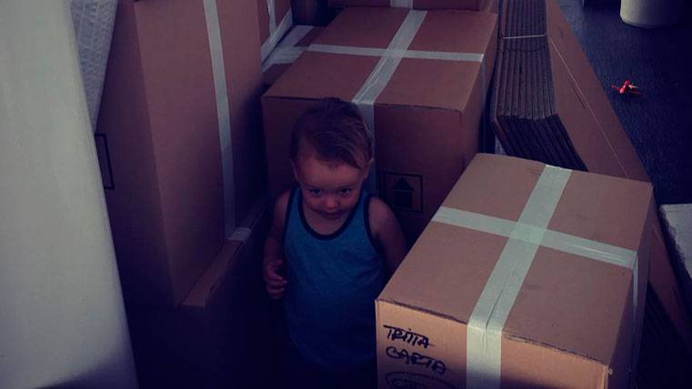 One of the children of Thomas Vermaelen between several boxes of mudanza