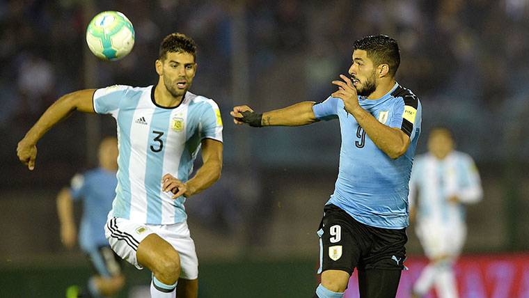 Luis Suárez, luchando por un balón con un jugador de Argentina