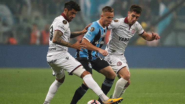 Arthur struggles by a balloon with two players of Lanús