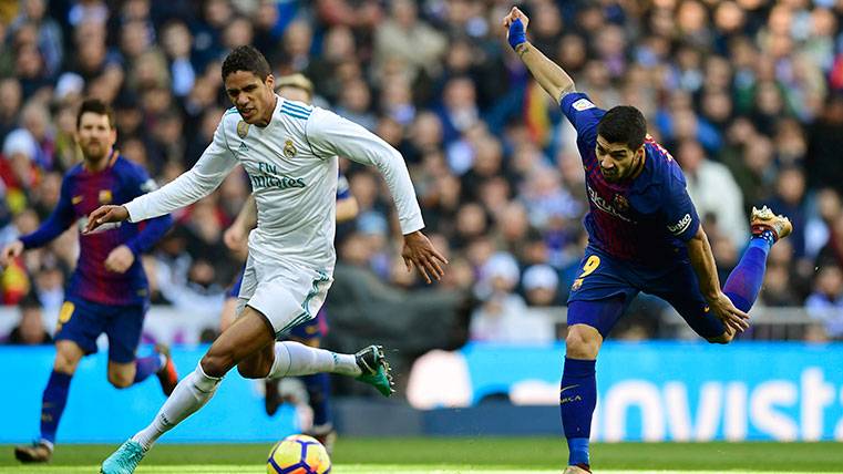 Raphaël Varane y Luis Suárez pugnan por un balón en el Clásico