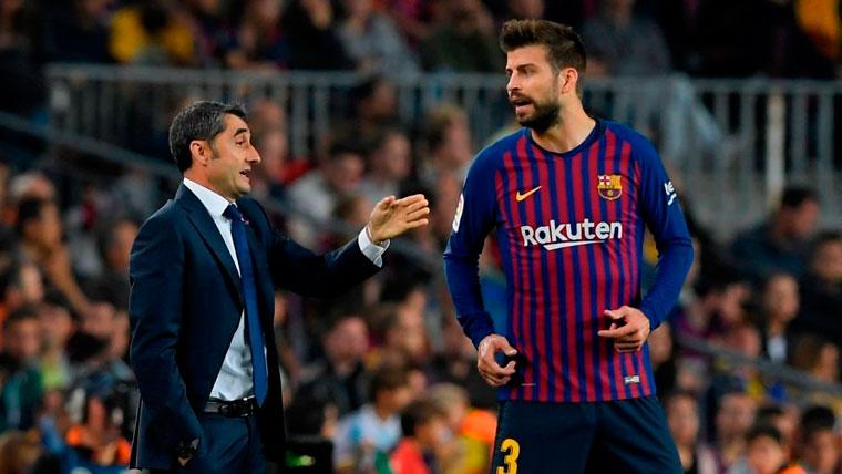 Ernesto Valverde y Gerard Pique conversan durante un partido del FC Barcelona