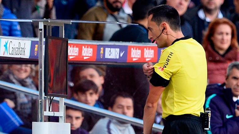 A referee consults the screen after speaking with the VAR