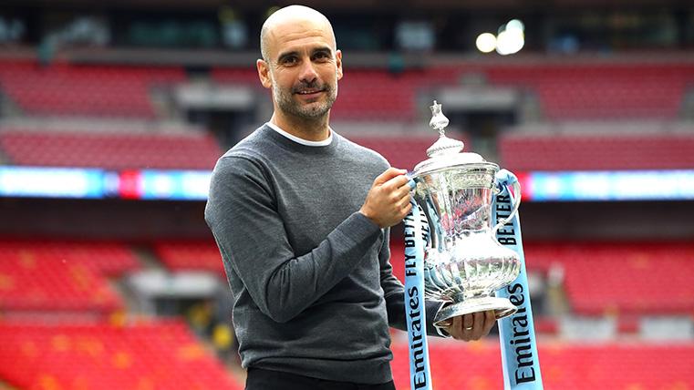 Pep Guardiola poses with the trophy of the FA Cup