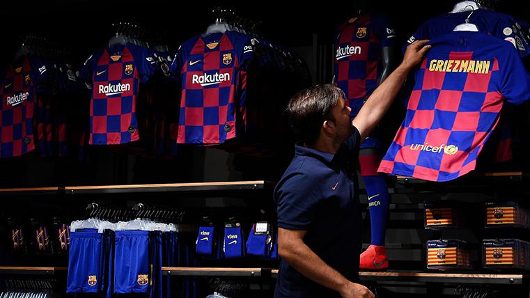 Un trabajador del Barça, colgando una camiseta de Griezmann en la Barça Store