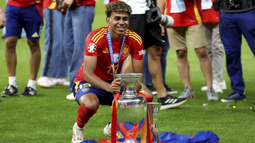 Lamine Yamal poses next to the Euro 2024 trophy